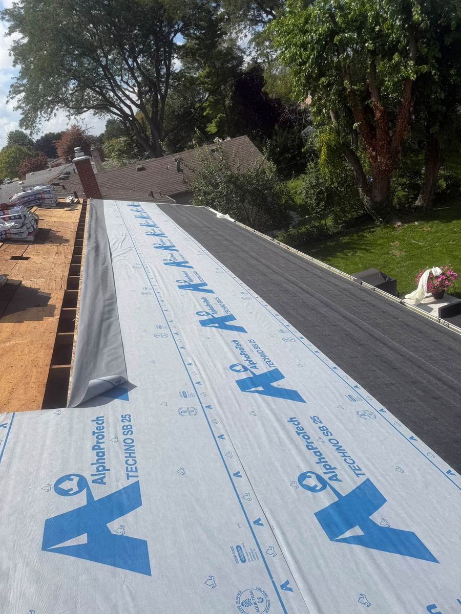 Synthetic underlayment rolled out along a roof before shingles go on